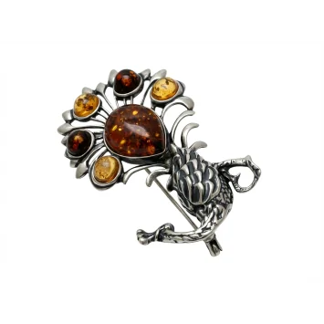 Detal broszki srebrnej oksydowanej z bursztynem bałtyckim, wzór smok i stylizowany kwiat na białym tle.